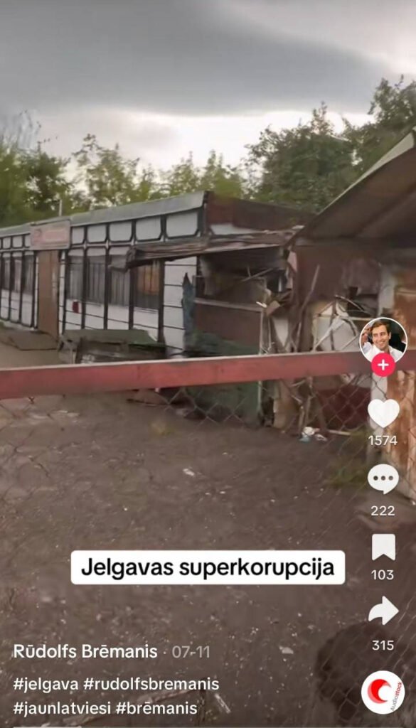 Tvērumā no TikTok video redzama nesakopta teritorija ar sagruvušu māju, attēla lejasdaļā ir uzraksts "Jelgavas superkorupcija"